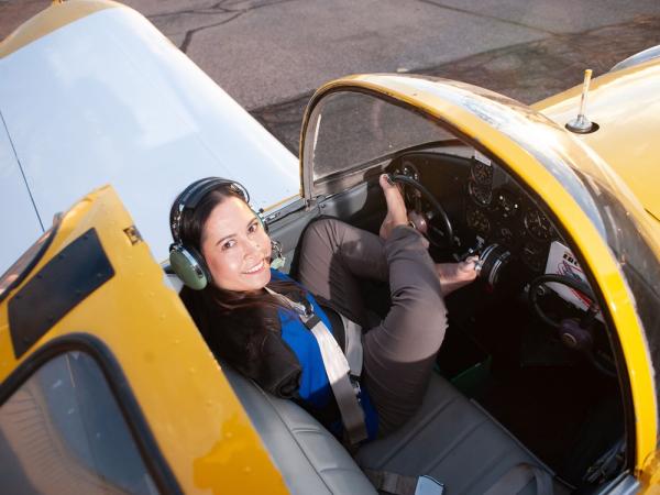 Jessica Cox sits in a small plane. She has her feet on the wheel, showing how she steers.