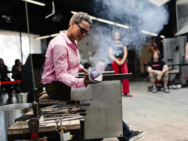 Debra Moore shapes blown glass while people watch