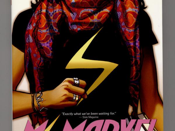 Cover of &quot;Ms. Marvel&quot; Volume 1 showing partial illustrated portrait of a young woman with a red scarf and gold lightning bolt on chest. It crops her eyes out. One hand is clasped in a determined fist.