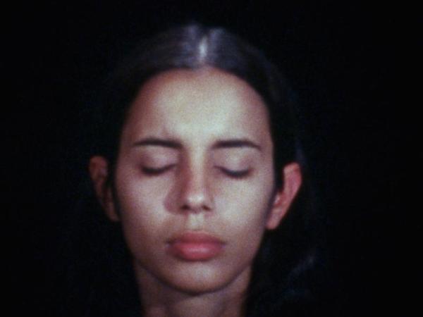 Close up of Ana Mendieta. Her eyes are closed and her expression is calm.