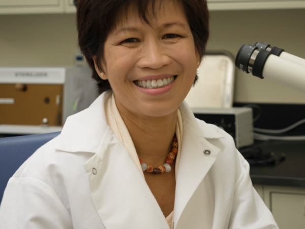 Nucharin Songsasen smiles while sitting in a lab, wearing a lab coat