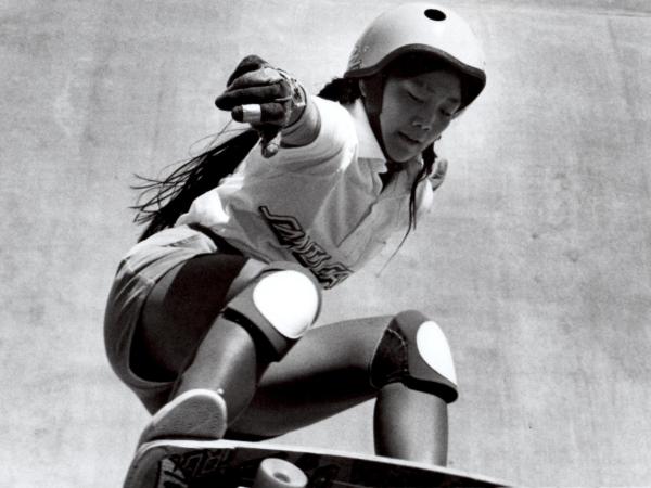 Judi Oyama crouched while riding a skateboard