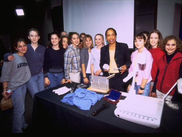 Dr. Patricia Bath holds ophthalmologist tools and posing with a large group of students