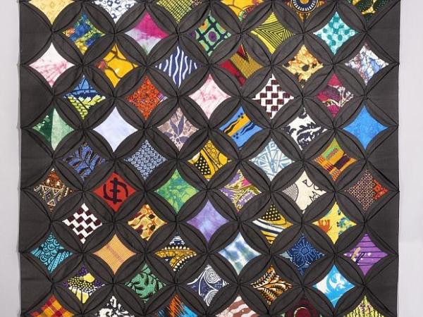 Quilt with colorful fabric diamonds against a black fabric