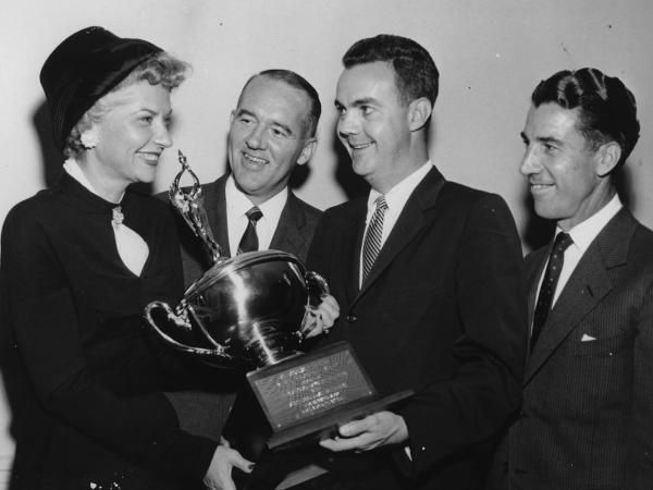 Brownie Wise being handed a Saleswoman of the Year Award by three men in suits