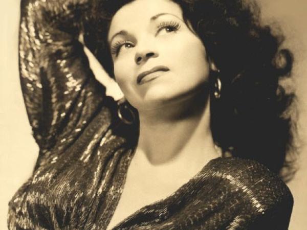 Black and white photograph of women wearing a sequined blouse striking a glamorous pose.