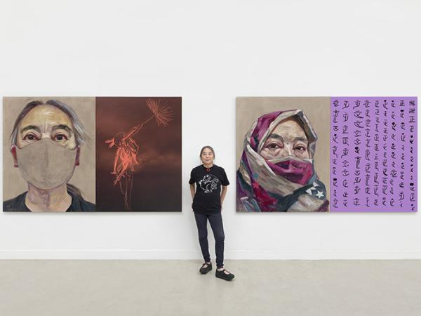  Hung Liu standing between two large and colorful self-portraits behind her