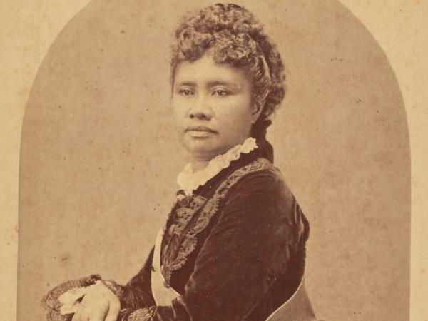 Queen Lili‘uokalani poses for a royal portrait. She wears a sash.