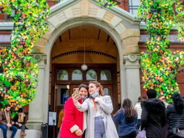 Two women taking a selfie in front of a building. 