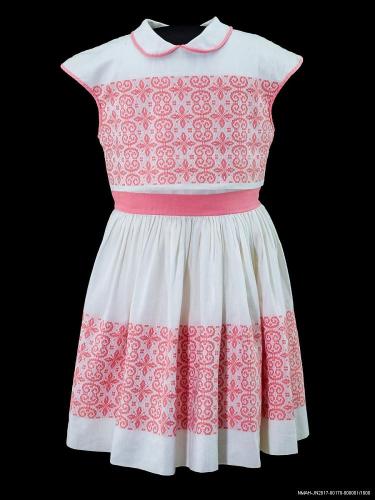 Short white dress with pink trim, patterns, and ribbon around the waist