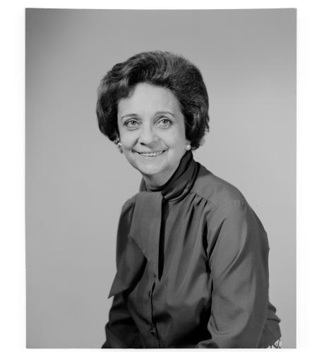 Portrait photograph of Farfante. She has short hair, is wearing earrings, and is smiling at the camera. This photograph was taken for a passport photo.