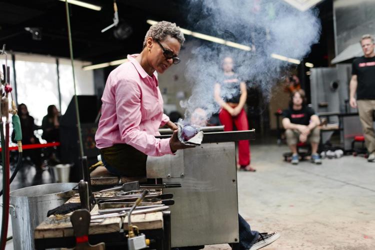 Debra Moore shapes blown glass while people watch