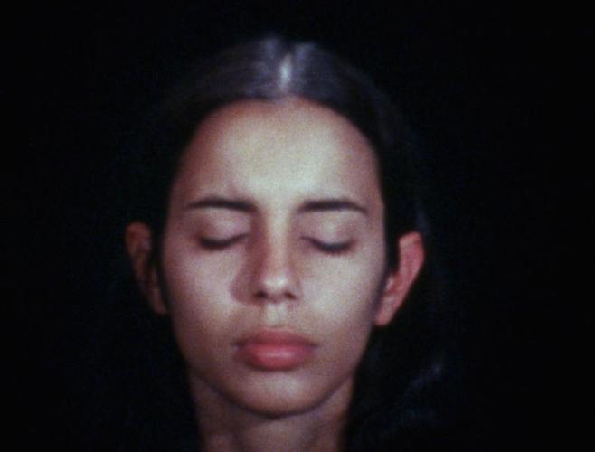 Close up of Ana Mendieta. Her eyes are closed and her expression is calm.