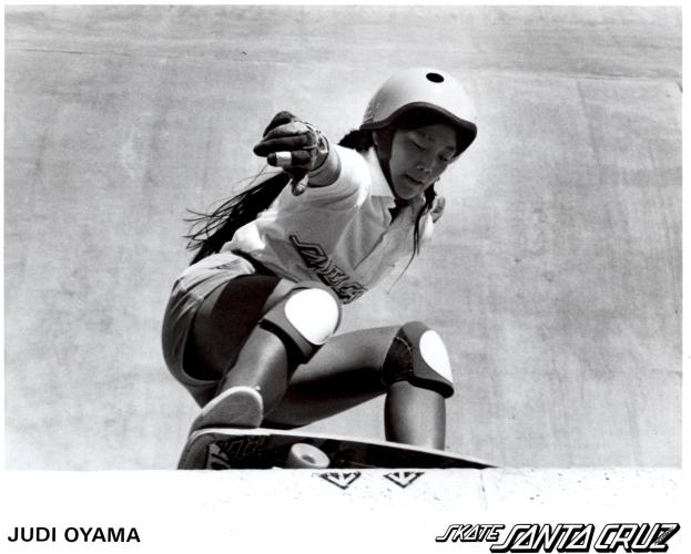 Judi Oyama crouched while riding a skateboard