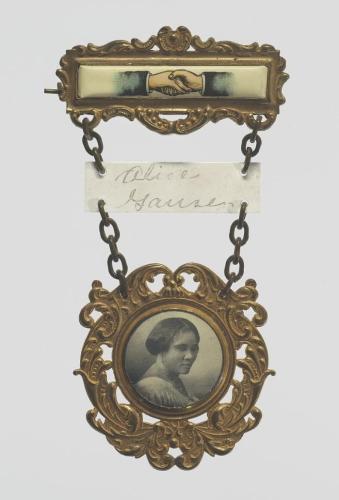 Three-tiered gold metal pin, with tiers connected by chains. Tier one has two people shaking hands, tier two is a piece of paper with &quot;Alice Gause&quot; written on it, and tier three is a portrait of Madame C.J. Walker.