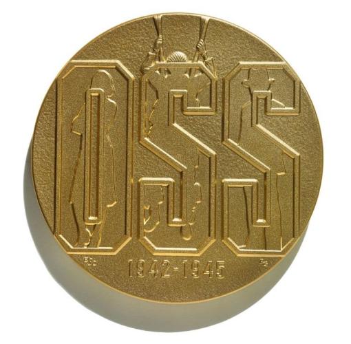 Gold commemorative coin that says &quot;OSS&quot; on front. Behind the letters are anonymous silhouettes, representing the American spies who worked for the OSS. At the bottom the coin says &quot;1942-1945.&quot;