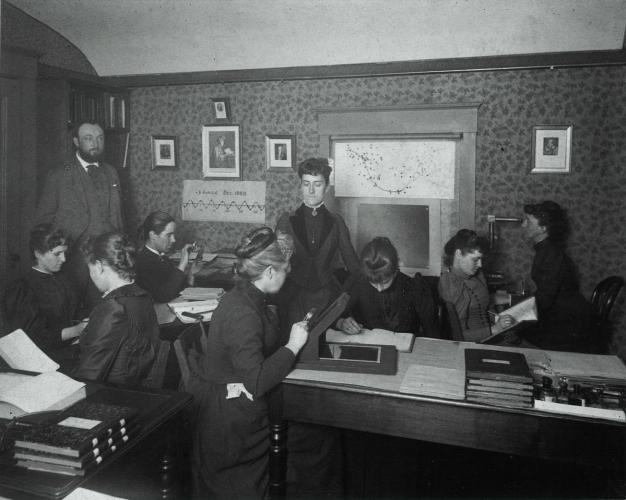 Women working as computers examine photographs of stars for astronomical data.