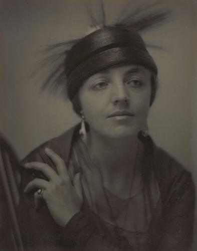 Black and white portrait of Katharine Rhoades from the chest up. Her hand is resting on her left shoulder.  