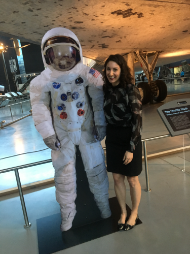 Dr. Emily Margolis stands next to a spacesuit