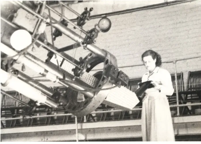 An aged black and white photograph of Nancy Grace Roman standing at a large telescope.