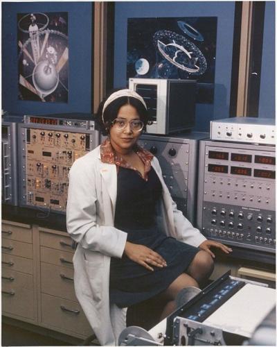 Color photo of Patricia Cowings in a lab coat sitting in front of machines. 