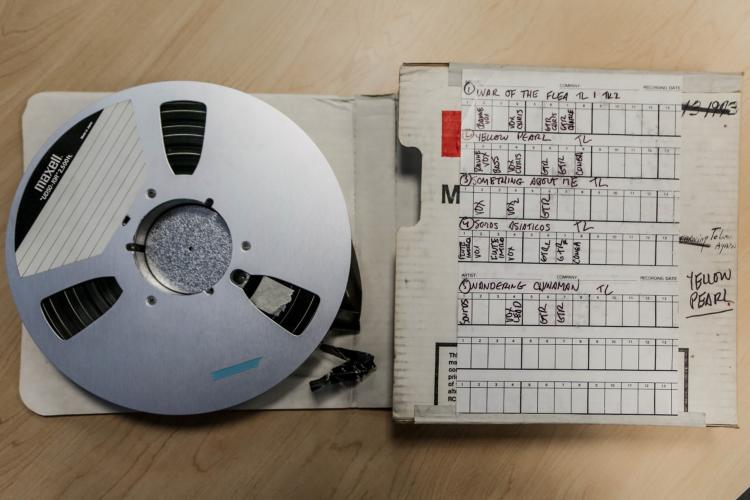 Photograph of a recording tape reel and storage box with a list of the recordings adhered to its exterior.