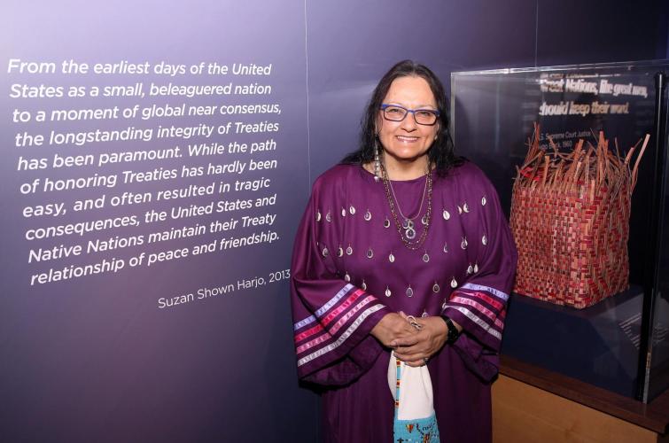 Suzan Shown Harjo in the exhibition, with a quote from her on her left and a woven basket in a glass case on her right.